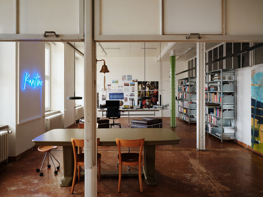Blick in das Atelier von Boris Szélpal im Emmenhof mit Arbeitstisch, Bücherregalen und Neon-Schriftzug.