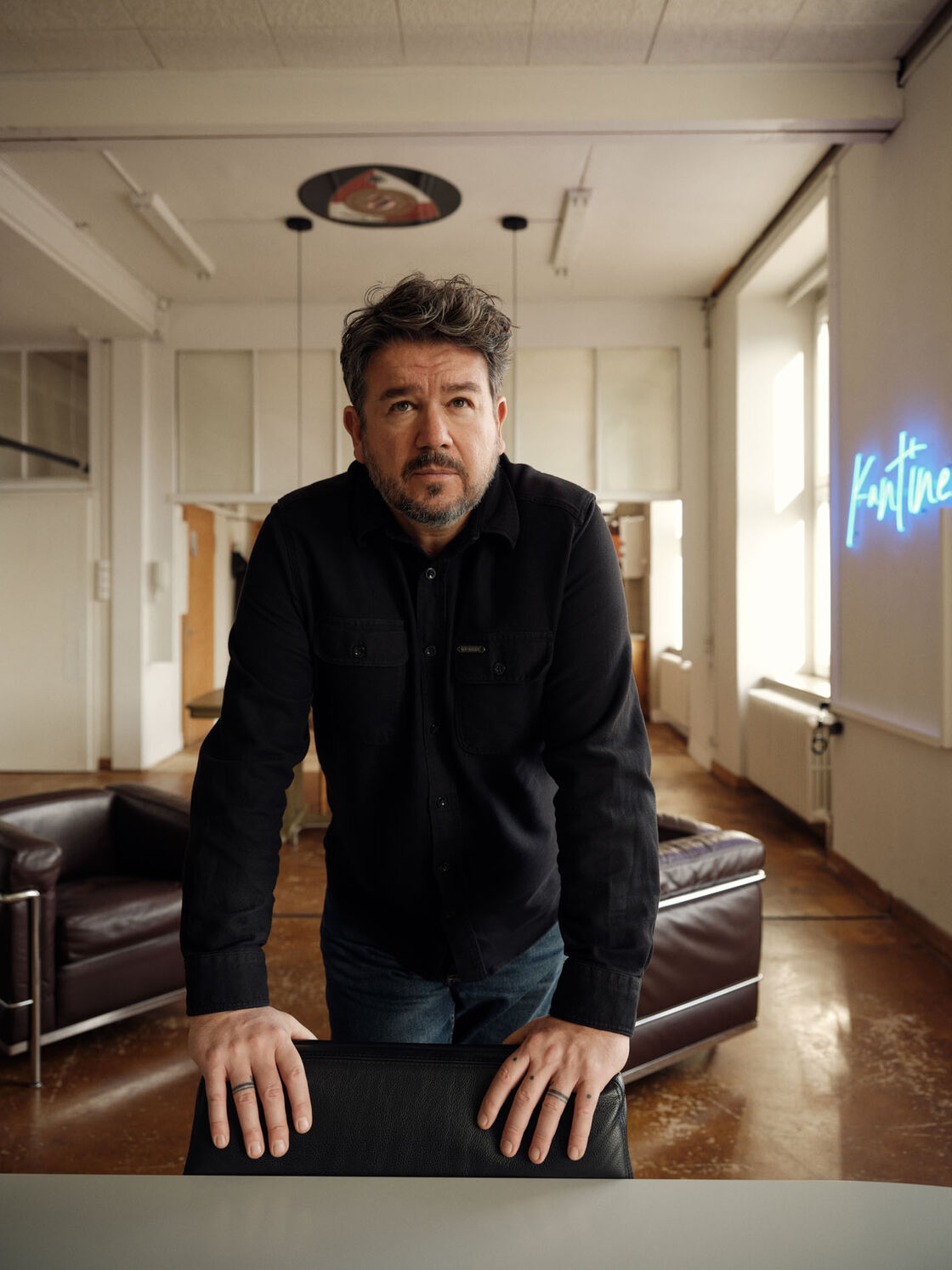 Boris Szélpal lehnt sich auf einen Tisch in seinem Atelier, direkte Haltung, konzentrierter Blick.